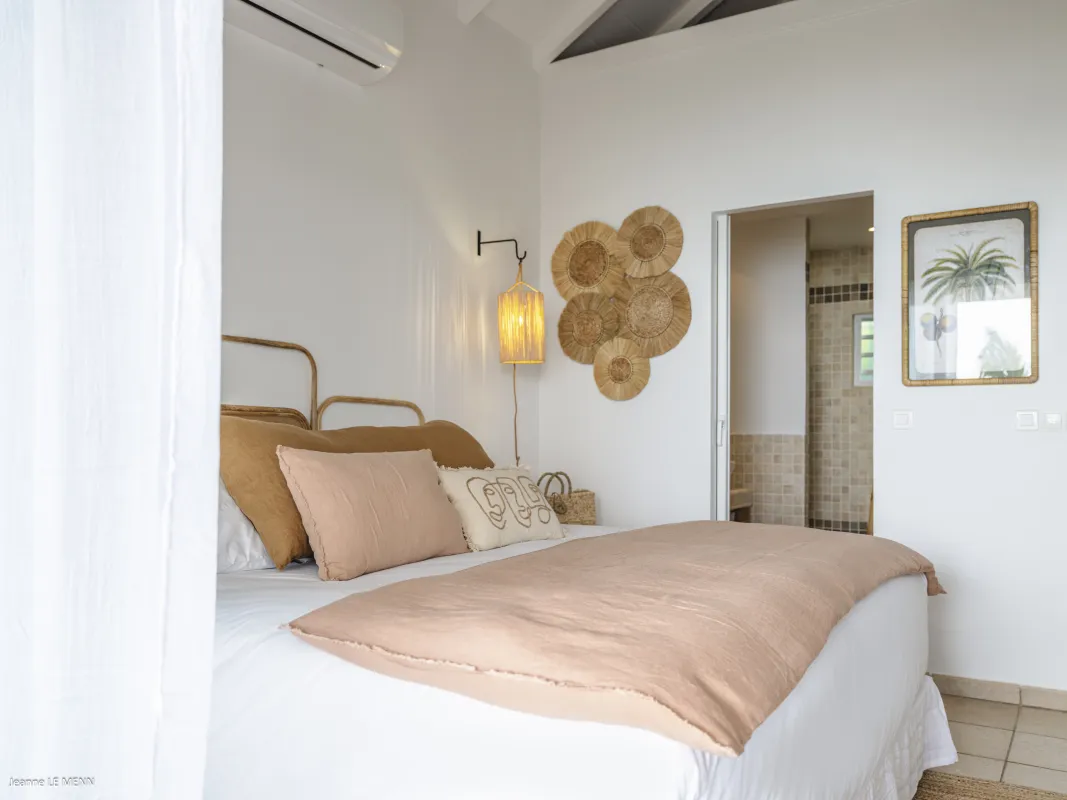 Villa Be Happy: Bedroom with neutral linens, woven wall decor, and doorway to an en-suite bathroom