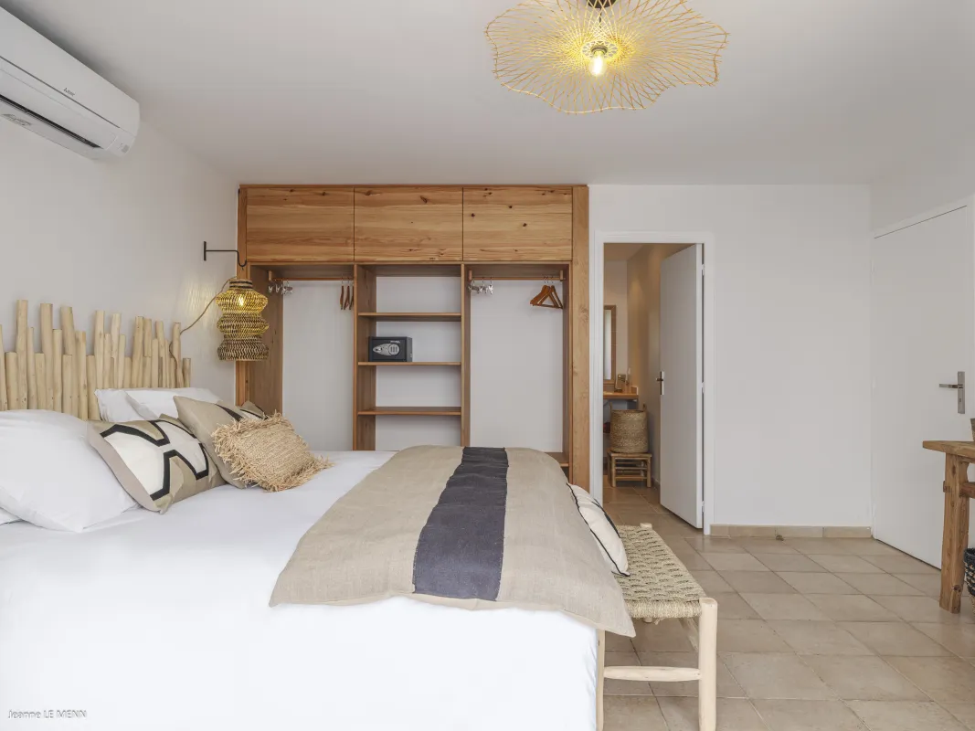 Villa Be Happy: Bedroom with white bedding, wooden headboard, open wardrobe, and doorway to an en-suite bathroom