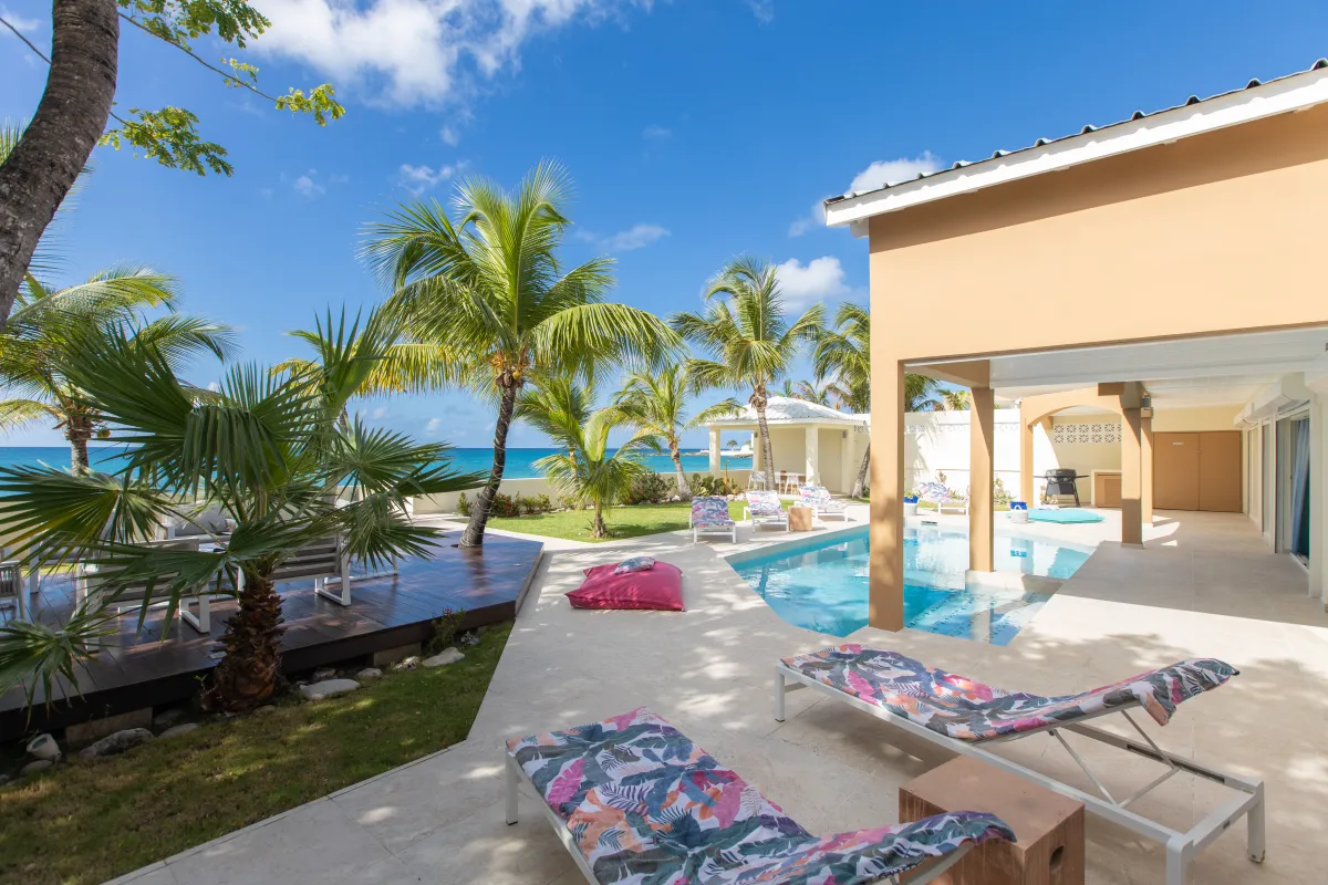 Villa Beach Secrets: Sun loungers on a pool terrace with palm trees and ocean views