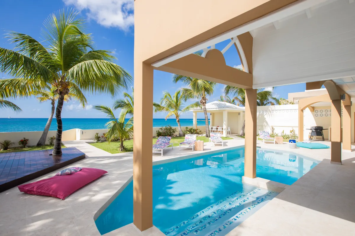 Villa Beach Secrets: Swimming pool and sun loungers on a terrace overlooking palm trees and the ocean