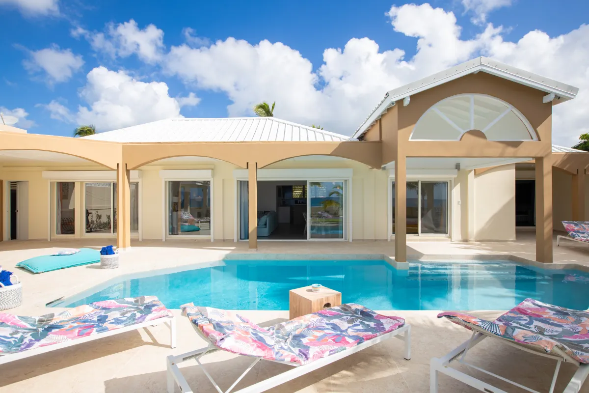 Villa Beach Secrets: Swimming pool and sun loungers on the terrace of a modern villa under blue skies