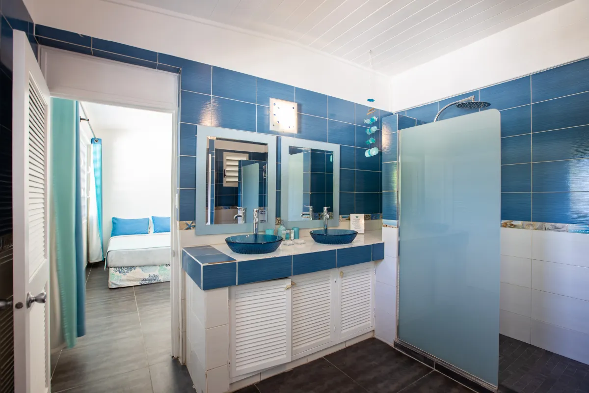 Villa Beach Secrets: En-suite bathroom with double vessel sinks, blue tiled walls, and a walk-in shower