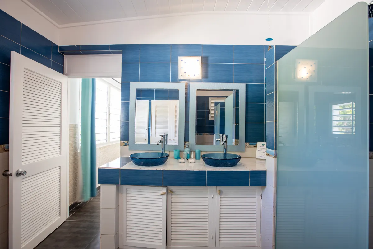 Villa Beach Secrets: Bathroom with double blue vessel sinks, twin mirrors, and white louvered cabinets