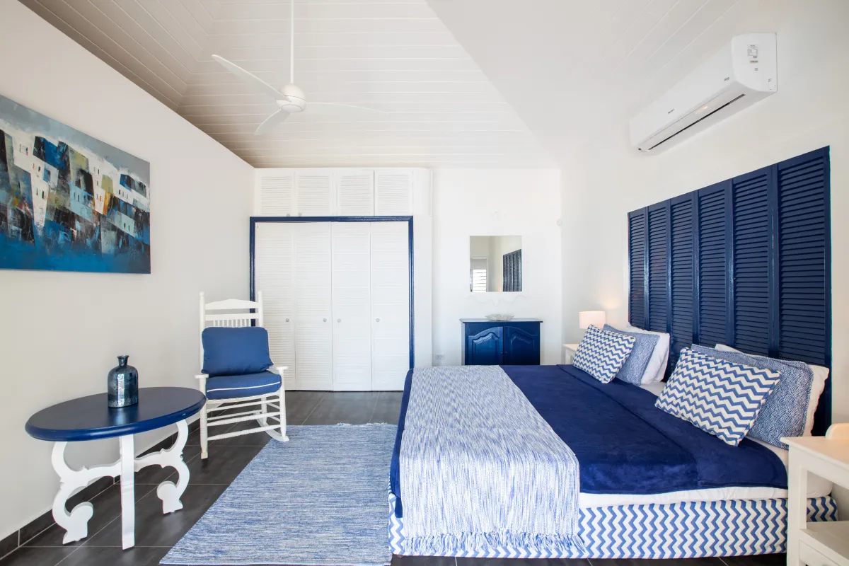 Villa Beach Secrets: Bedroom with blue and white decor, king bed, rocking chair, and vaulted ceiling