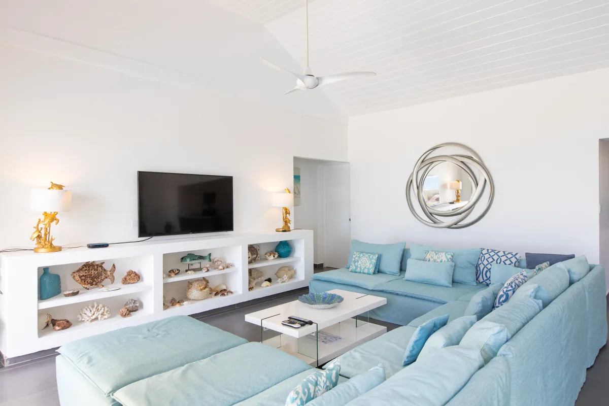 Villa Beach Secrets: Living room with a large light blue sectional sofa, television, and coastal decor