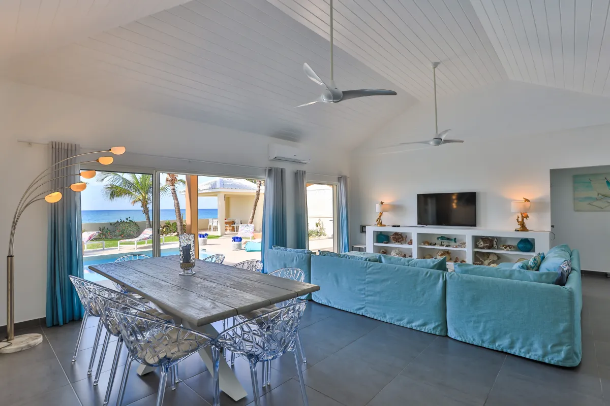 Villa Beach Secrets: Open-concept living and dining area with ocean views and sliding glass doors