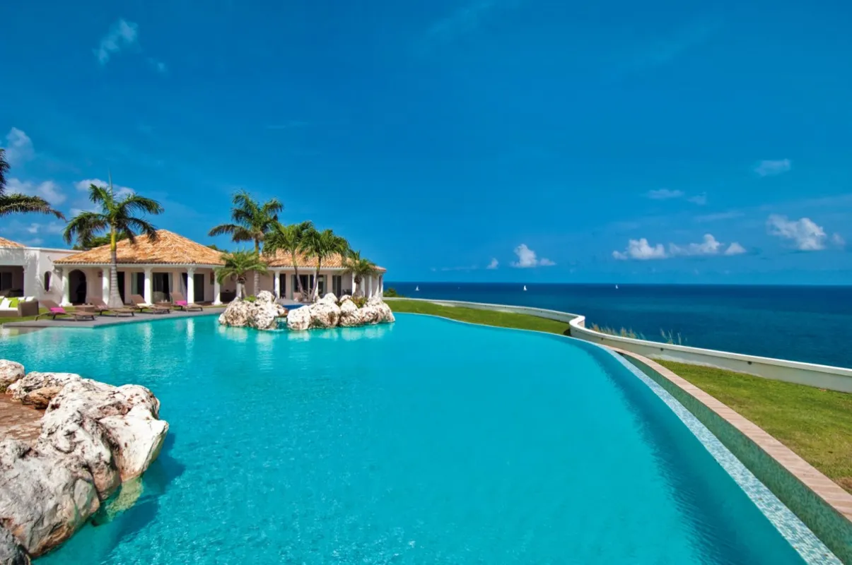 Villa Belle Étoile: Large infinity pool overlooking the ocean with rock formations and villa in the background