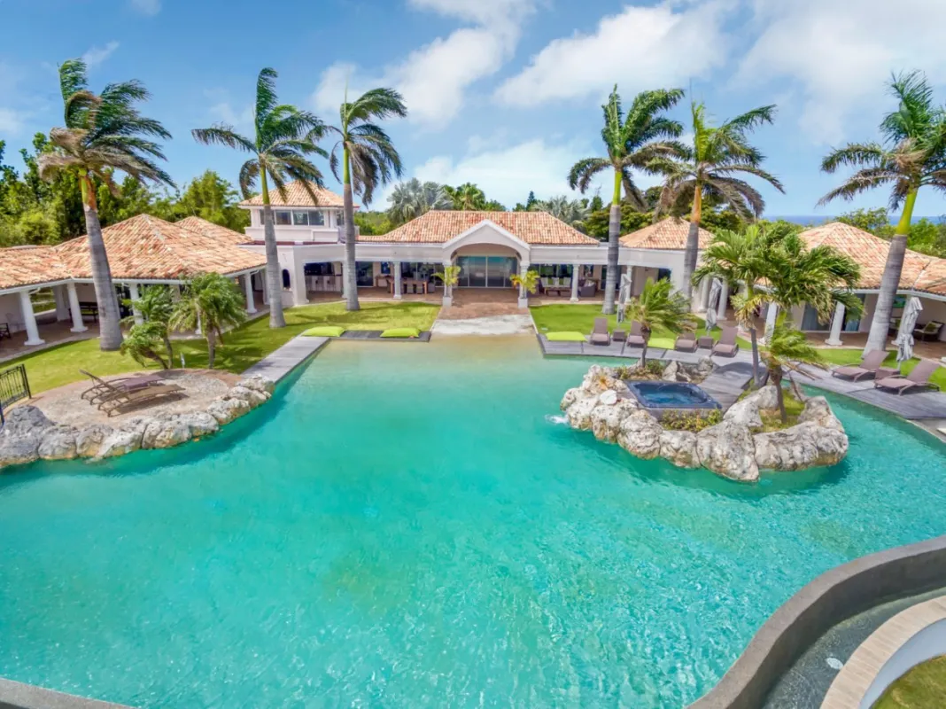 Villa Belle Étoile: Large lagoon swimming pool with a rock island hot tub and palm trees facing a villa