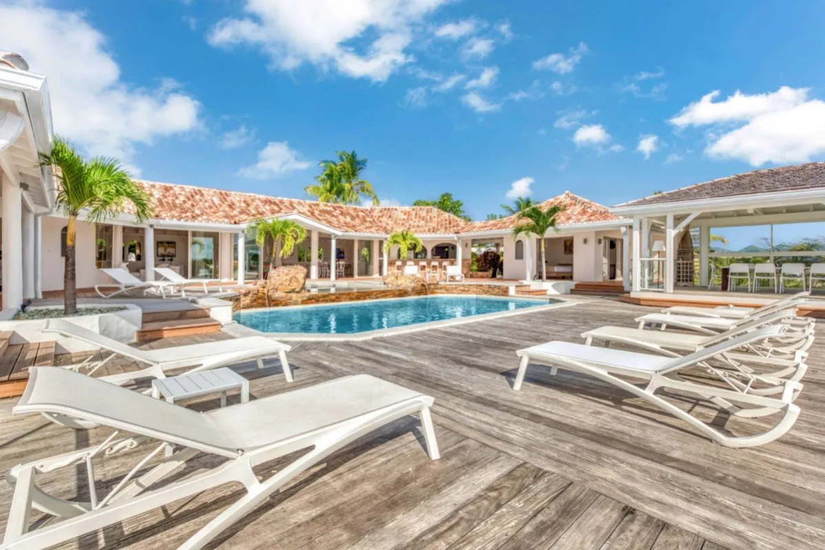 Villa Belle Fontaine: Wooden deck with sun loungers surrounding a swimming pool outside a single-story villa