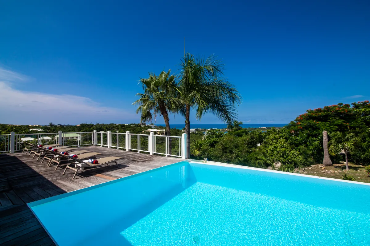 Villa Callisto: Swimming pool and wooden sun deck with loungers overlooking tropical greenery and the ocean