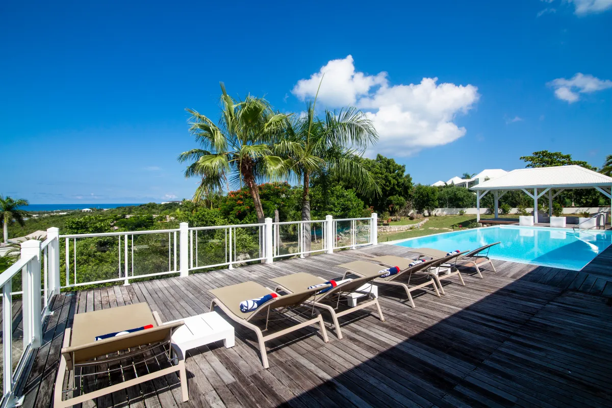 Villa Callisto: Wooden pool deck with sun loungers overlooking lush greenery and the sea