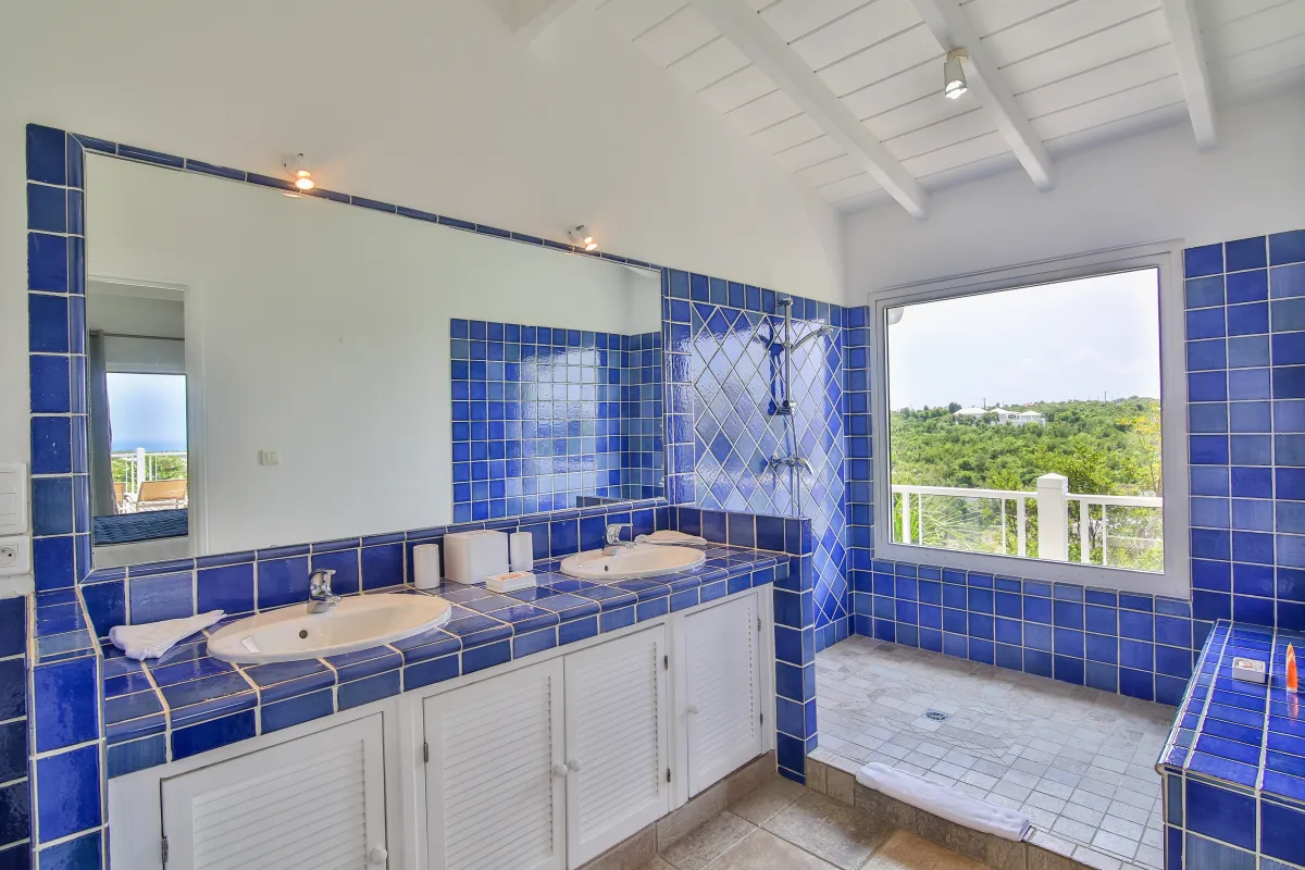 Villa Callisto: Bathroom with blue tiled double vanity, large mirror, and walk-in shower by a window