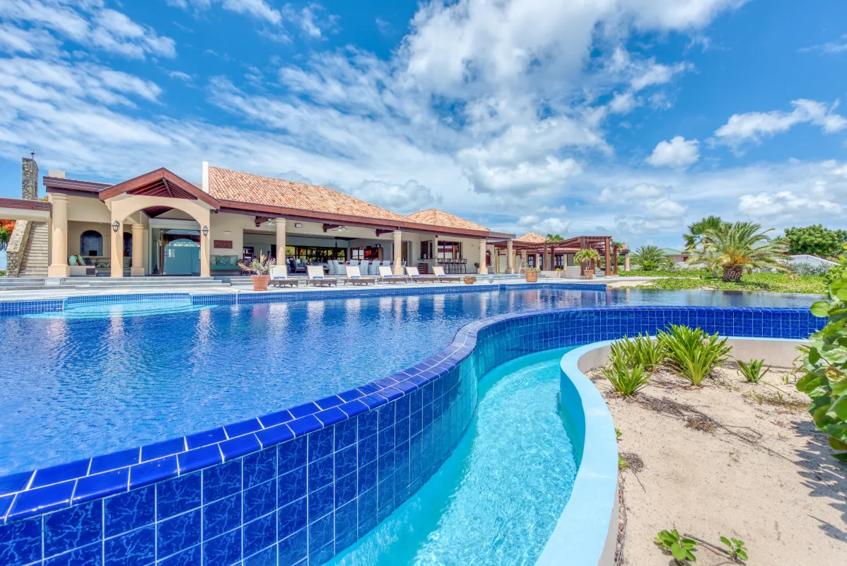 Villa Casa de la Playa: Large swimming pool with blue tiles outside a vacation villa under a partly cloudy sky