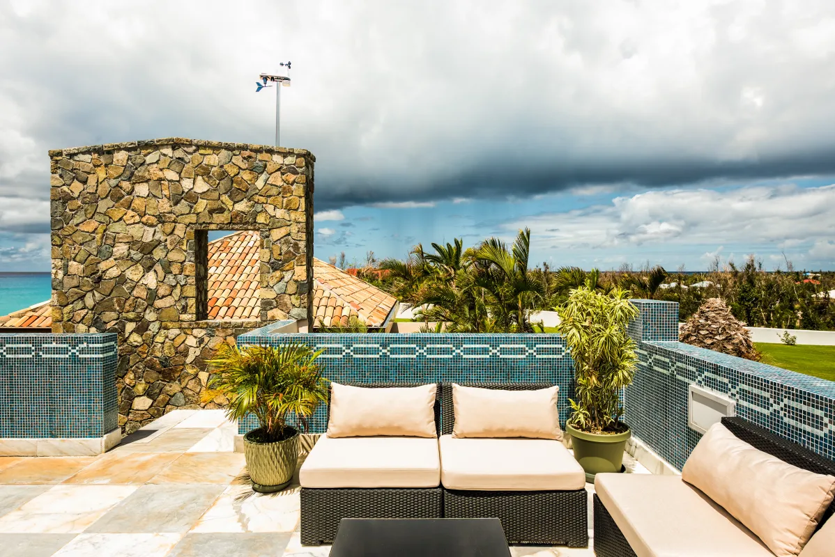 Villa Casa de la Playa: Rooftop terrace with cushioned lounge seating, blue tile railings, and distant ocean view