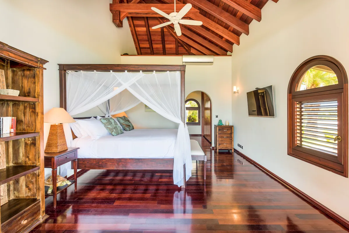 Villa Casa de la Playa: Bedroom with four-poster bed, vaulted wood ceiling, and polished hardwood floors