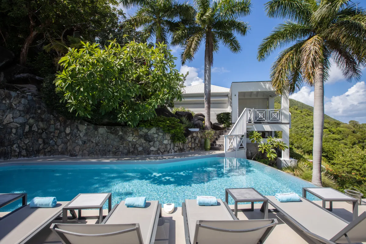 Villa Casa Sand: Swimming pool with sun loungers surrounded by tall palm trees and hillside landscaping