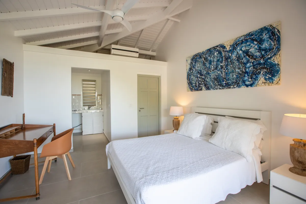 Villa Casa Sand: Bedroom with a white bed, vaulted ceiling, abstract wall art, and a wooden writing desk