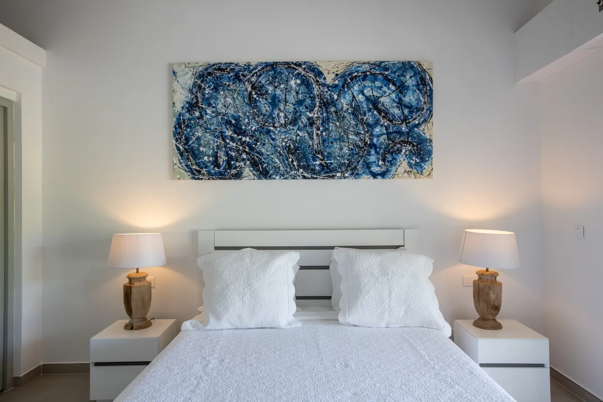 Villa Casa Sand: Bedroom with white bedding, matching nightstands with lamps, and blue abstract artwork