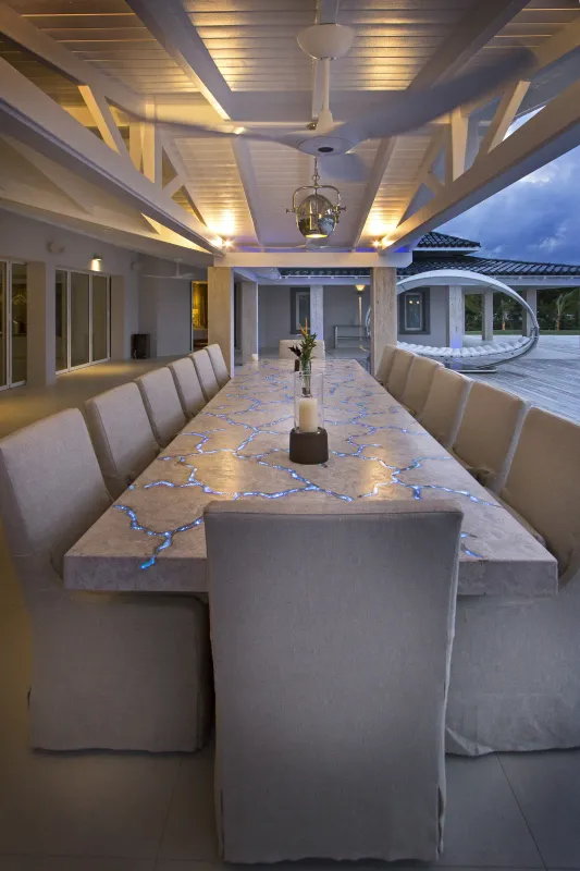 Villa C'est la Vie: Covered terrace featuring a long dining table with illuminated accents and slipcovered chairs at dusk