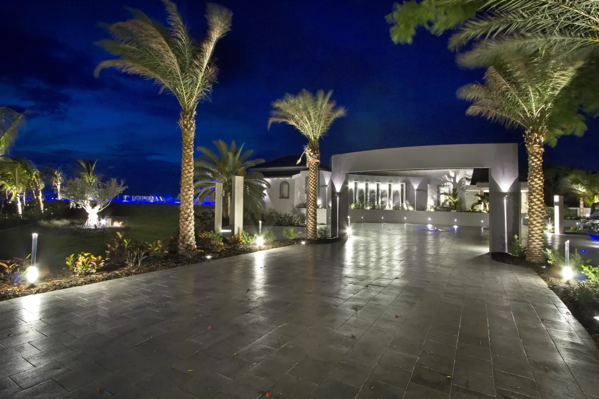 Villa C'est la Vie: Paved driveway and entrance courtyard lined with palm trees illuminated at night