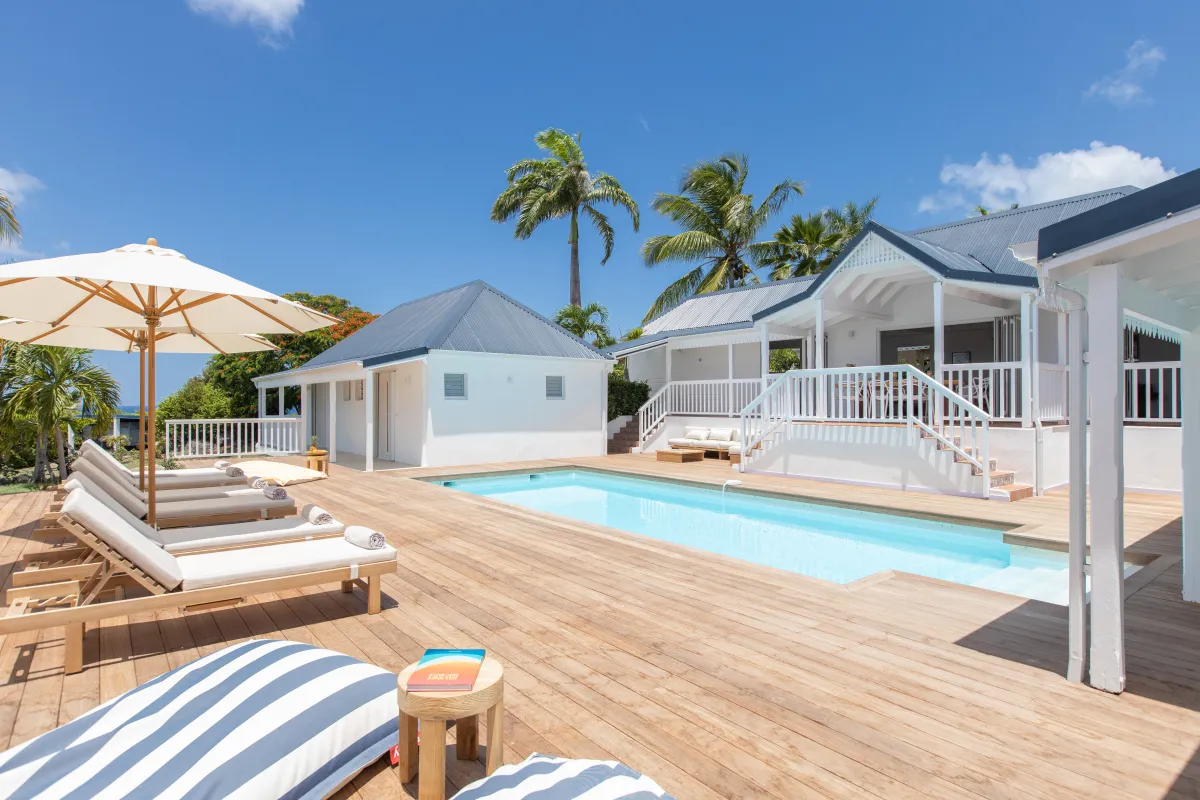 Villa Coco Paillette: Swimming pool and wooden sun deck surrounded by white cottages and palm trees