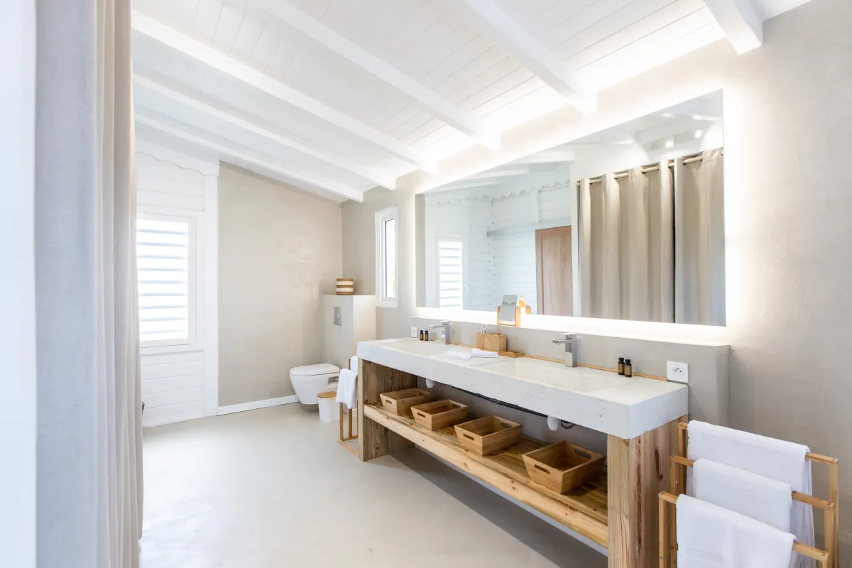 Villa Coco Paillette: Modern bathroom with double vanity, large backlit mirror, and white wood-beamed ceiling