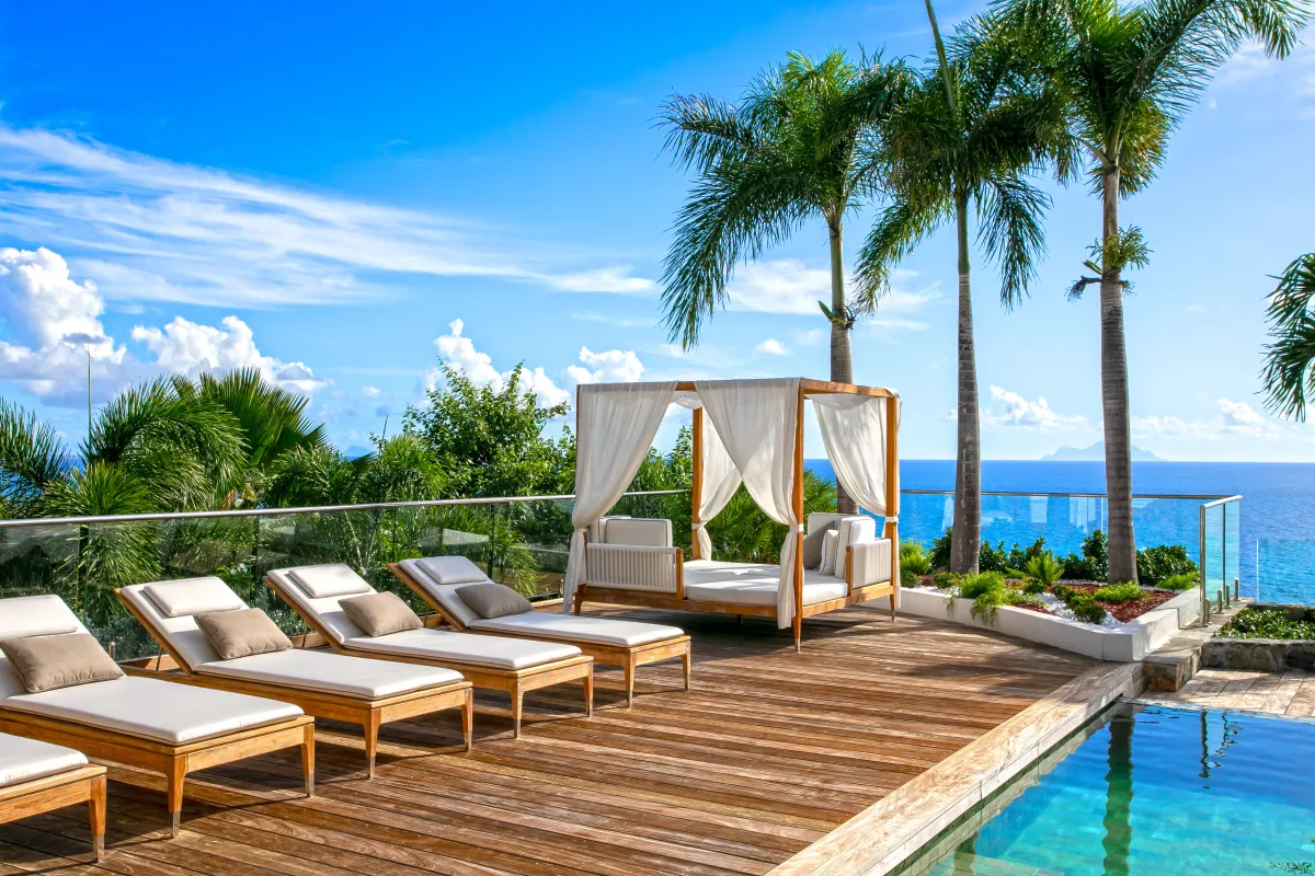 Villa Emeraude: Wooden sun deck with loungers, a cabana daybed, palm trees, and ocean views