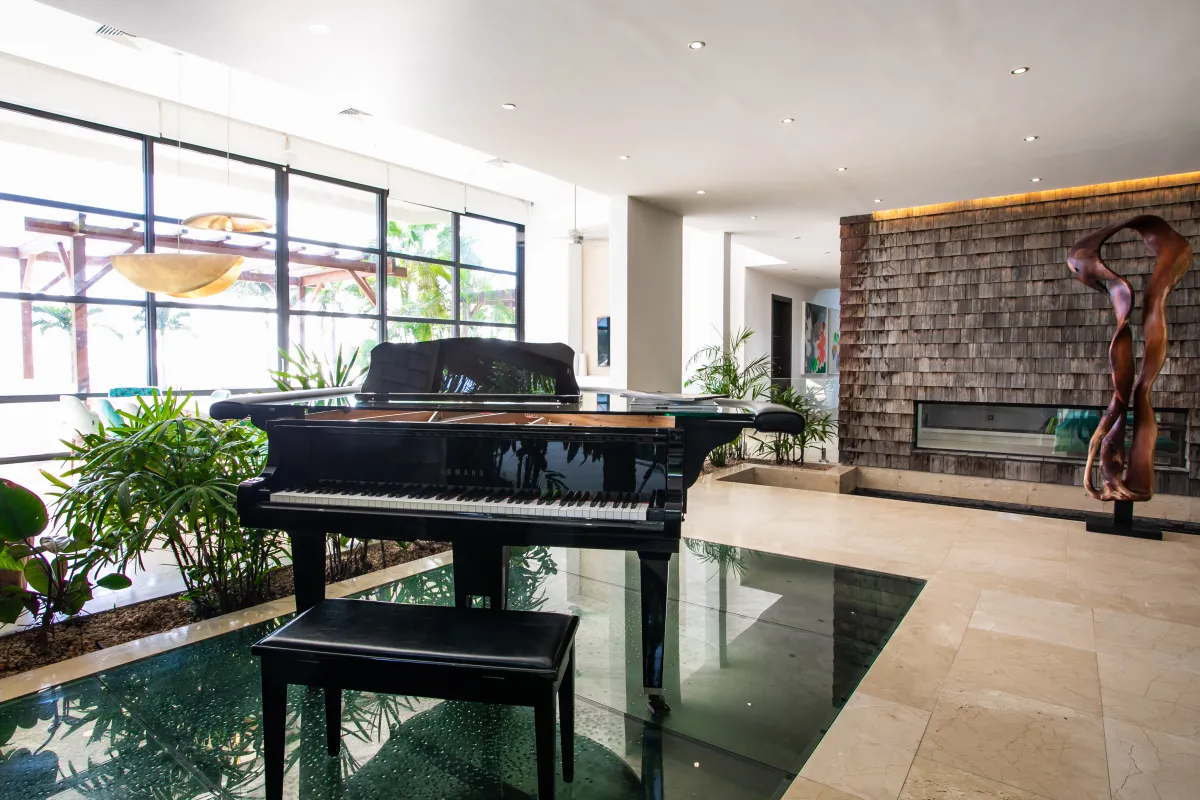 Villa Emeraude: Black grand piano positioned over glass flooring in a bright modern open living area