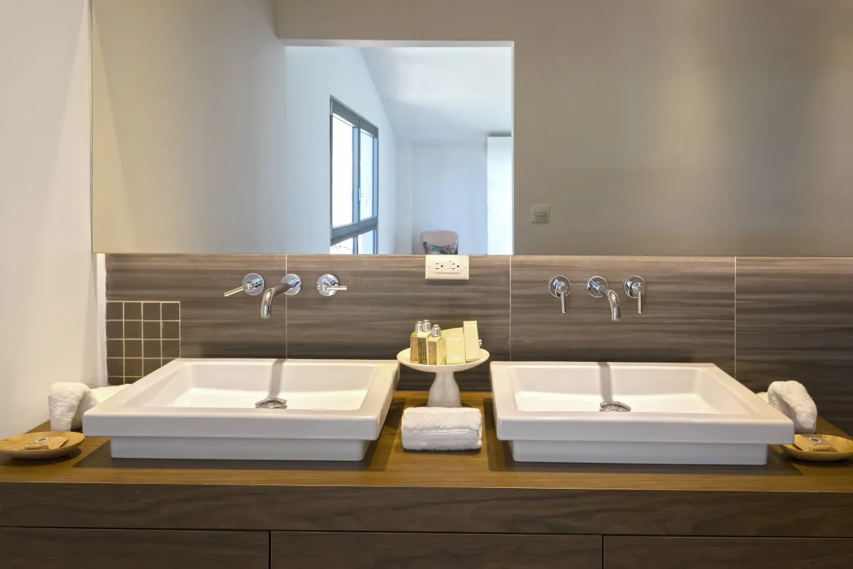 Villa Emeraude: Modern double vanity with white square sinks, wall-mounted faucets, and toiletries