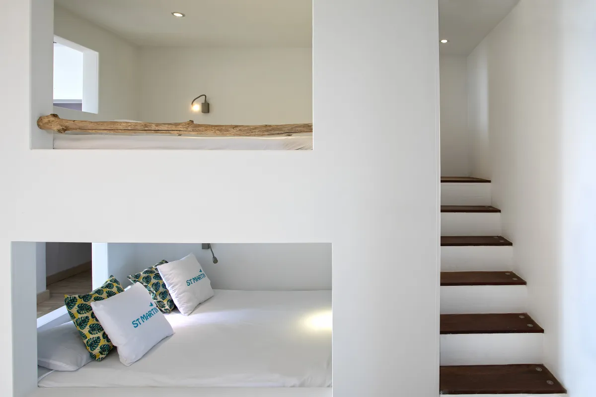 Villa Emeraude: Built-in bunk beds recessed into white walls next to wooden stairs