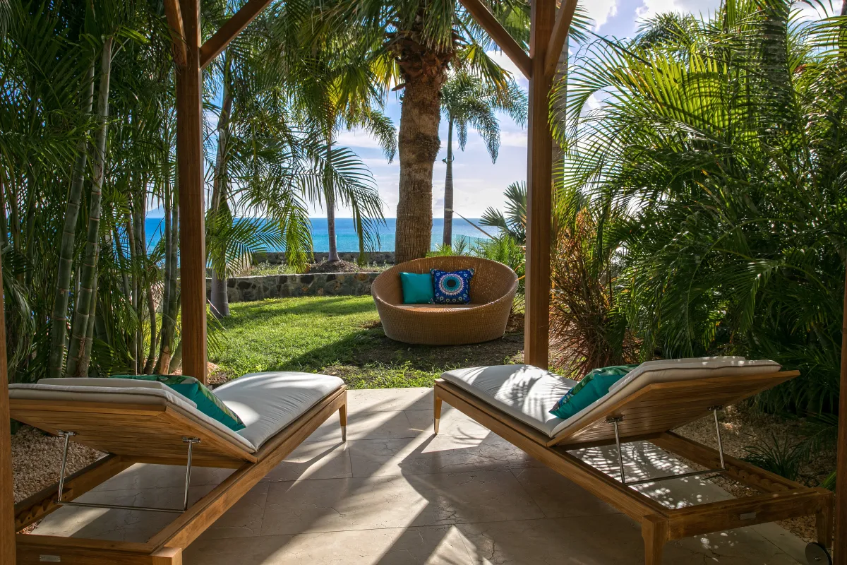 Villa Emeraude: Covered terrace with wooden sun loungers looking out toward palm trees and the ocean