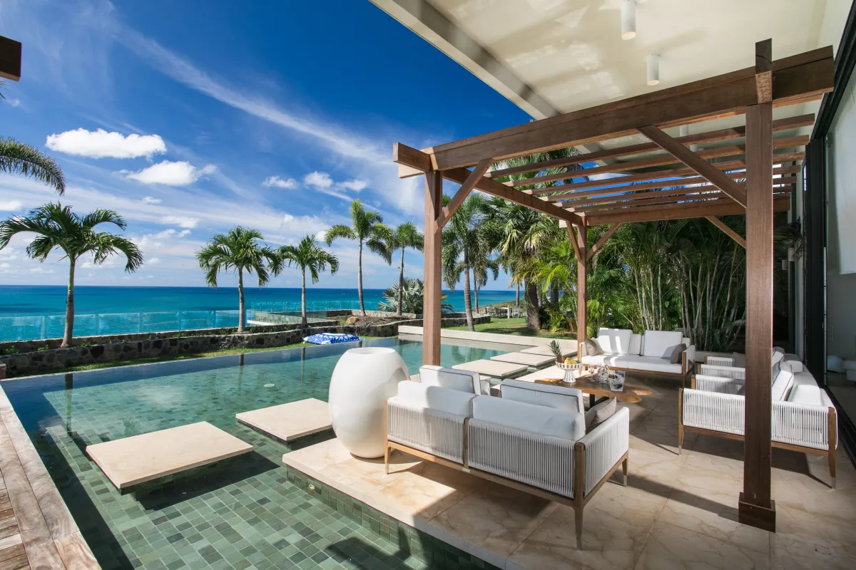 Villa Emeraude: Outdoor lounge under a wooden pergola beside a swimming pool overlooking the ocean