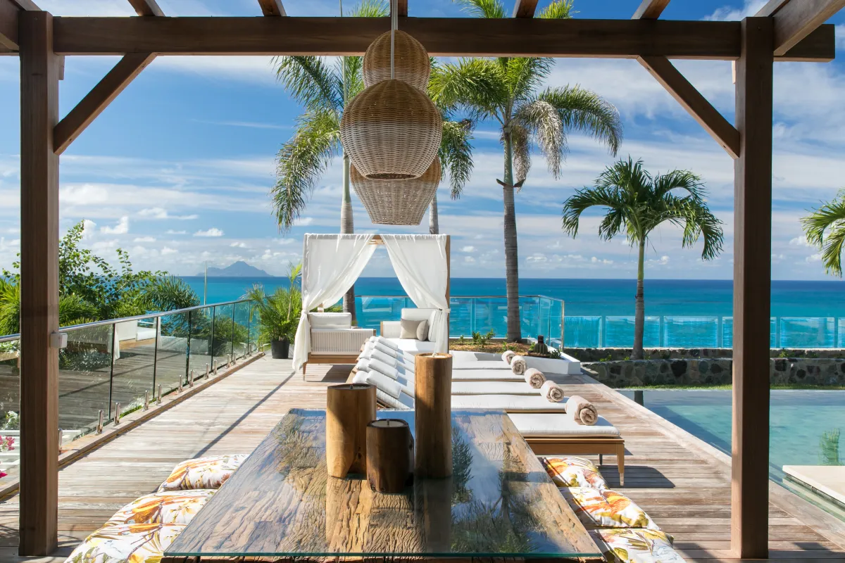 Villa Emeraude: Wooden deck with dining table and sun loungers overlooking palm trees and the ocean