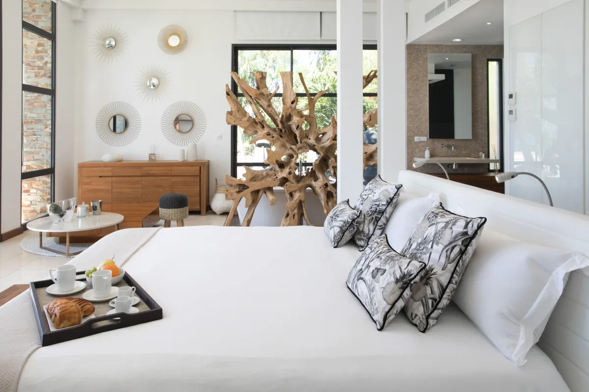 Villa Emeraude: Bright bedroom featuring a white bed with breakfast tray and large driftwood sculpture