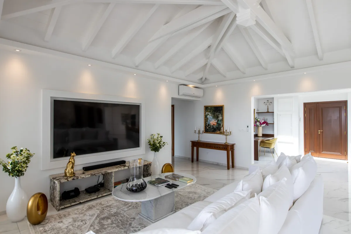Villa Fleurs de Lys: Living room with vaulted ceiling, large wall-mounted television, and white sectional sofa