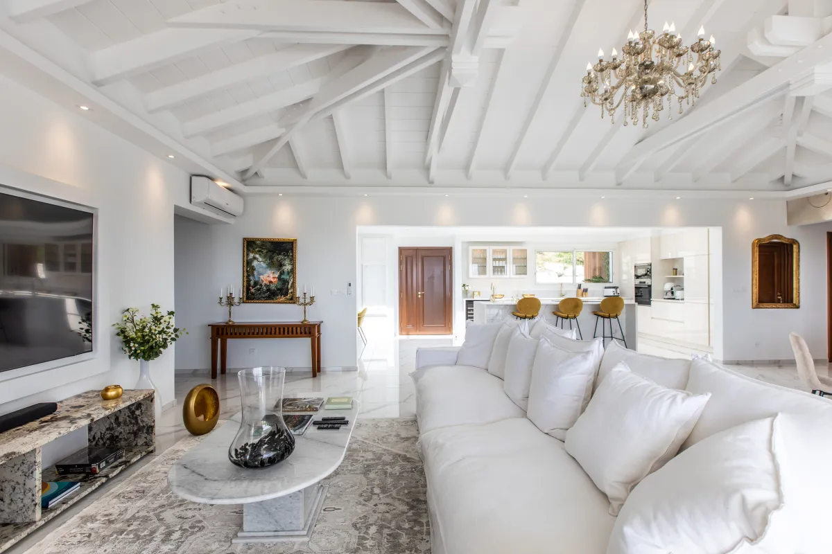 Villa Fleurs de Lys: Spacious living area with white sofa, high vaulted ceiling, chandelier, and open kitchen in the background