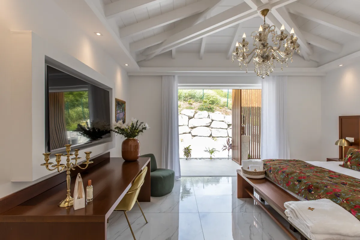 Villa Fleurs de Lys: Spacious bedroom with vaulted ceilings, chandelier, television, and open doors to patio