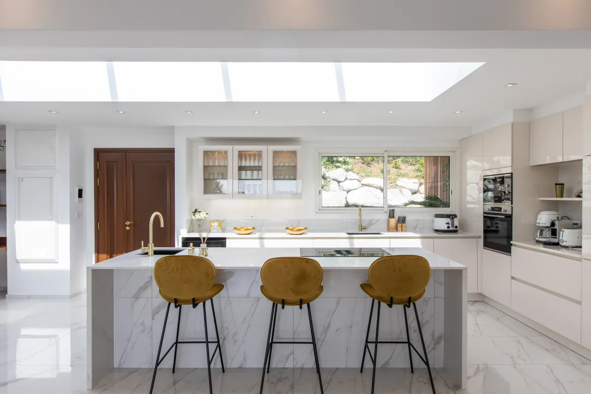 Villa Fleurs de Lys: Modern kitchen with white marble island, three yellow bar stools, and overhead skylight