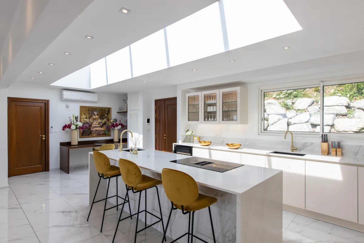 Villa Fleurs de Lys: Modern kitchen featuring a marble island with yellow bar stools under a large skylight