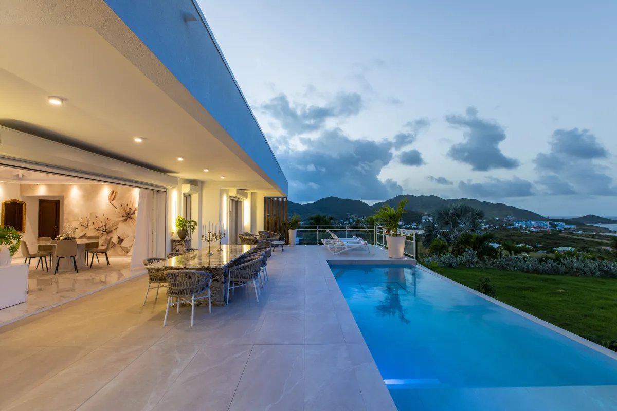 Villa Fleurs de Lys: Infinity pool and covered terrace with outdoor dining overlooking green hills at twilight
