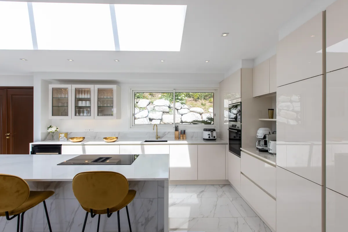 Villa Fleurs de Lys: Modern kitchen with large island, bar stools, white cabinetry, and skylight