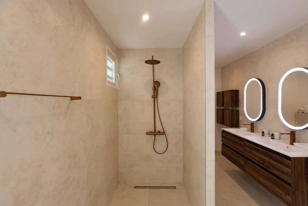 Villa Greystone: Modern bathroom with walk-in shower and double vanity featuring illuminated oval mirrors