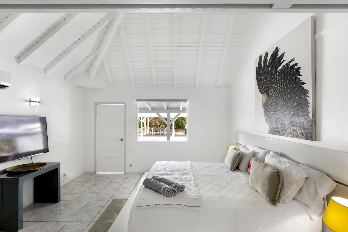 Villa Greystone: Bright white bedroom with a king bed, vaulted ceiling, and television