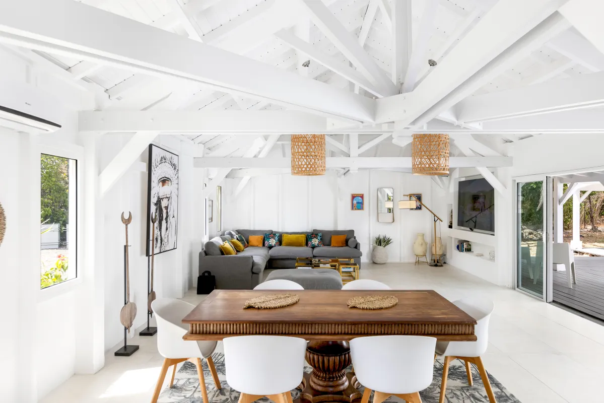 Villa Greystone: Open-concept living and dining area with white exposed beam ceilings and wooden dining table