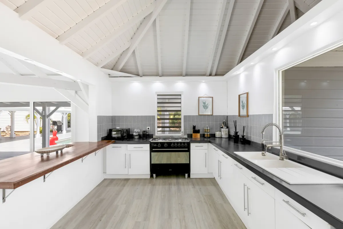 Villa Greystone: Modern open kitchen with vaulted white ceiling, dark countertops, and breakfast bar