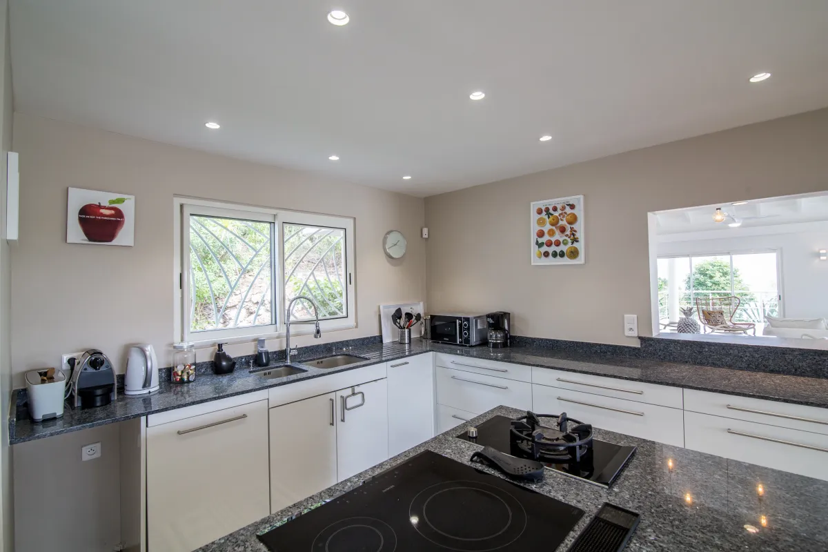 Villa Imagine: Modern kitchen with granite countertops, island cooktop, and white cabinetry