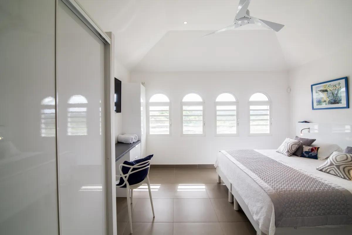 Villa Imagine: Bright white bedroom with a king bed, desk, and arched windows