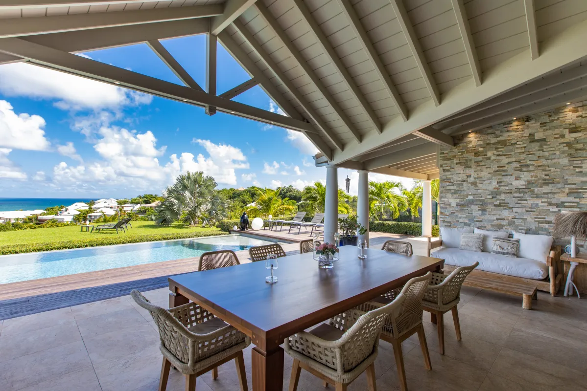 Villa Indigo Pearl: Covered terrace with a dining table overlooking a swimming pool and the ocean