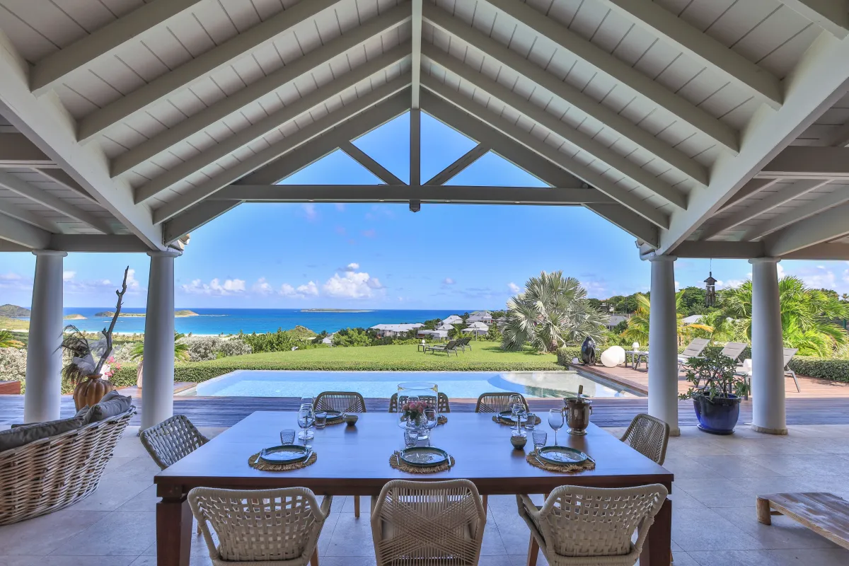 Villa Indigo Pearl: Covered terrace with a dining table overlooking a swimming pool and the ocean