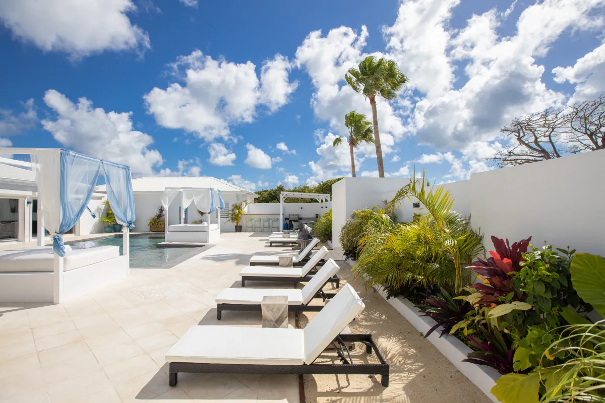 Villa Infinity Blue: Swimming pool terrace with sun loungers and canopy daybeds under a blue sky